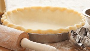 empty pie crust with rolling pin and other baking tools