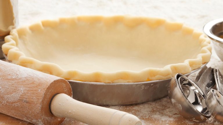 empty pie crust with rolling pin and other baking tools